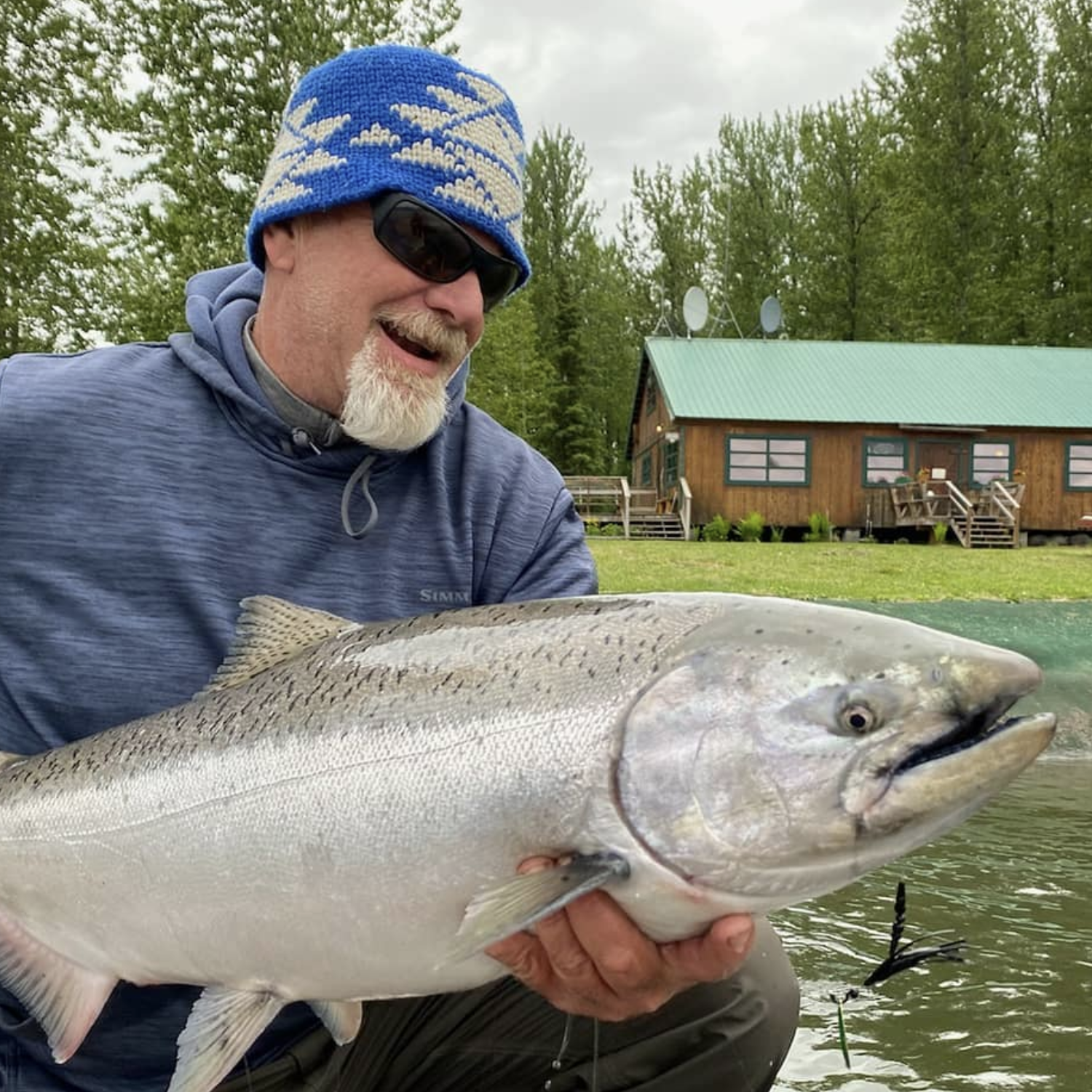 Guests holding a chrome king salmon in front of Lake Creek Lodge in Alaska