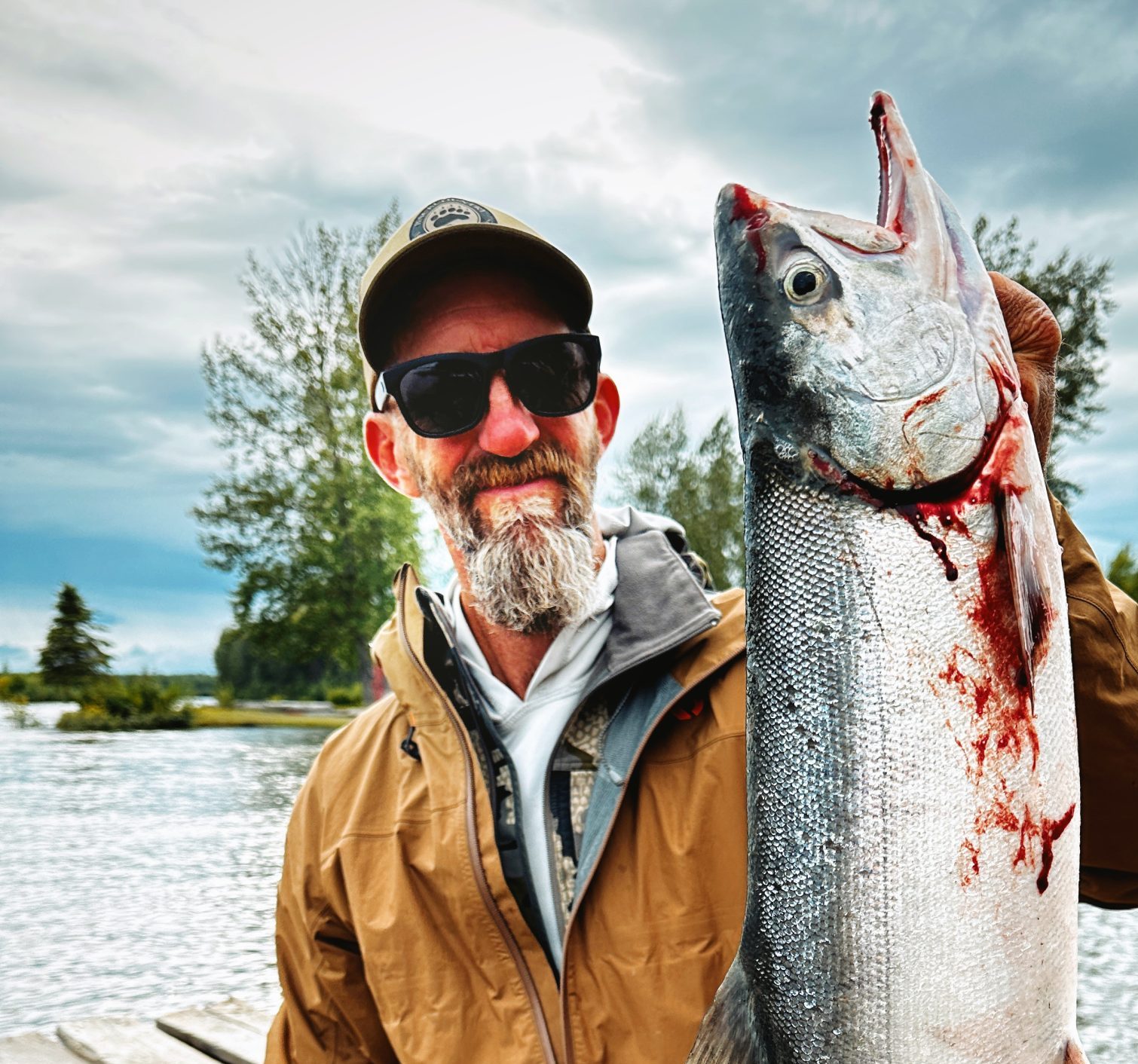 Guests holding a large silver salmon off the dock at Lake Creek Lodge in Alaska